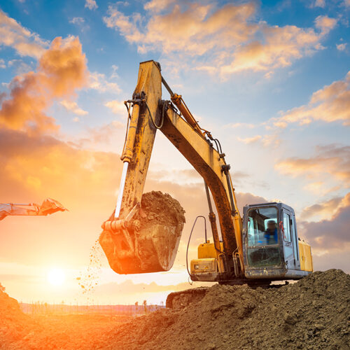 excavator in construction site on sunset sky background