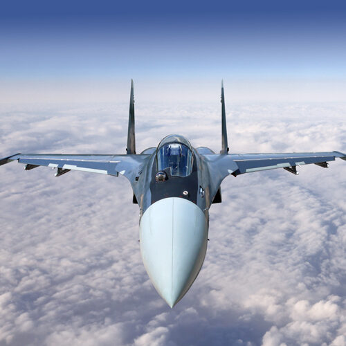 Modern military jet fighter airplane flying above the clouds.